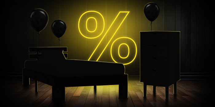 Črna postelja in komoda s črnimi baloni pred svetlo rumenim znakom za odstotek na temnem lesenem podu.